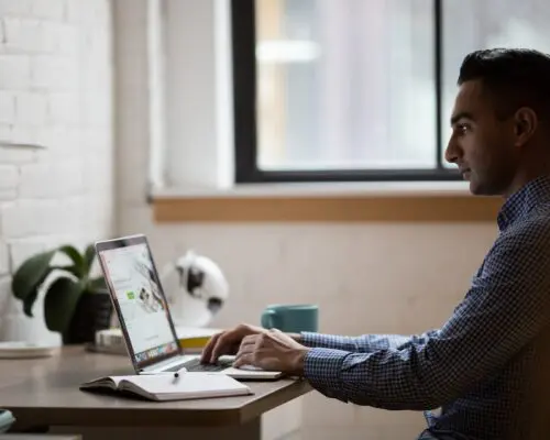 man typing on laptop at desk