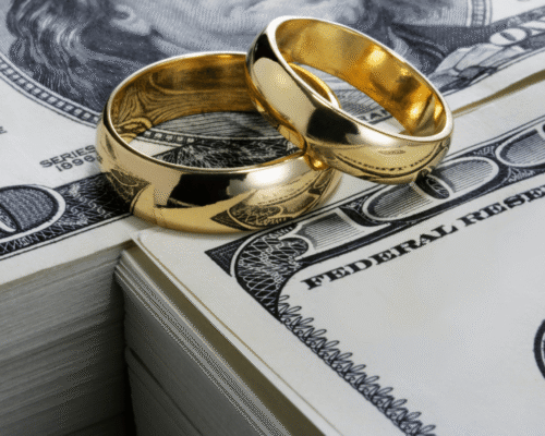 Two gold wedding rings placed on a stack of hundred-dollar bills, symbolizing QDRO retirement divorce Montgomery County PA. The image highlights pension division Pennsylvania divorce, 401(k) QDRO PA, equitable distribution retirement accounts, and Qualified Domestic Relations Order PA requirements in divorce settlements.