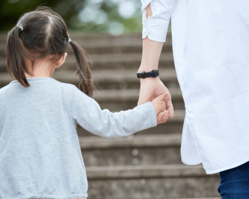 A small child holding an adult's hand while walking up stairs, representing the consideration of child age custody input Pennsylvania in legal decisions.