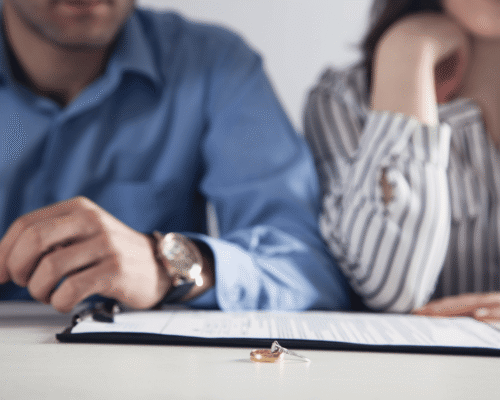Wedding rings resting on top of legal papers between two people, representing the conversation of how to tell partner you want a divorce Montgomery County.