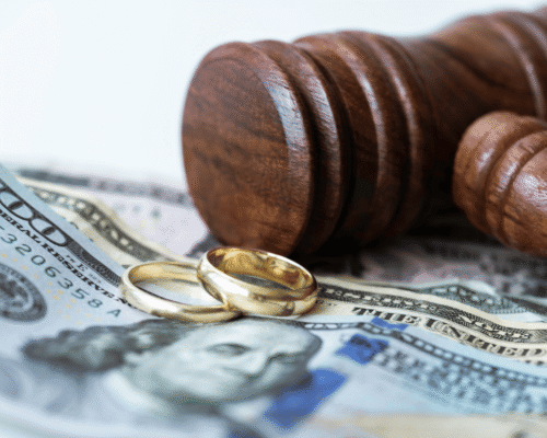 Judge’s gavel rests beside two gold wedding rings on top of hundred-dollar bills, symbolizing dividing royalties divorce Pennsylvania. The image highlights creative income divorce PA, intellectual property divorce PA, film residuals divorce, and artist income equitable distribution in high-asset divorce cases.